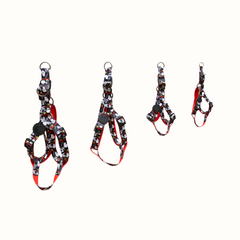 Arnês Zooz, de cores preto e branco com detalhes vermelhos e figuras do snoopy. Vista de frente, de varios tamanhos, sobre fundo branco.