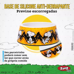 Informações do comedouro ZOOZ para animal, em plástico, com design do Snoopy, cor amarelo e preto, com imagens do personagem. Vista Frontal, sobre fundo branco.