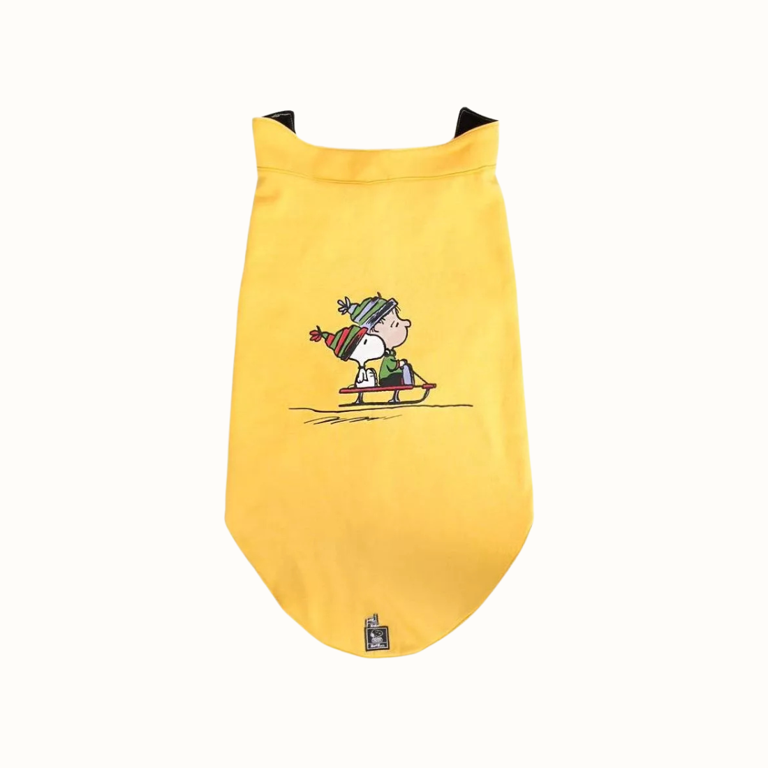 Colete Zooz para cão na cor amarela, com detalhes em preto, com estampa do personagem a deslizar na neve com um gorro e cachecol, acompanhado do Woodstock. Vista frontal, sobre fundo branco.