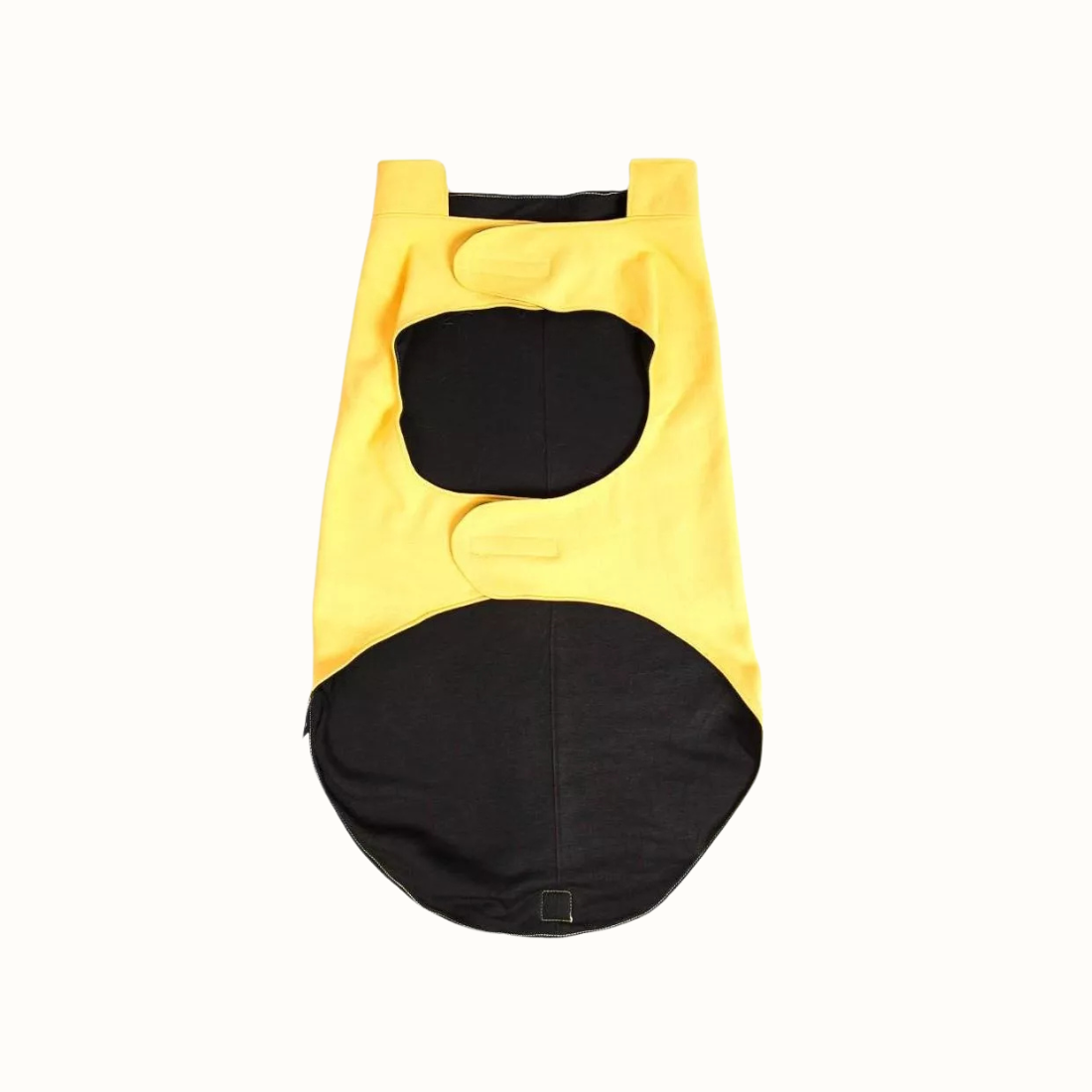 Colete Zooz para cão na cor amarela, com detalhes em preto, com estampa do personagem a deslizar na neve com um gorro e cachecol, acompanhado do Woodstock. Vista inferior, destacando a abertura para fixação da trela e um reforço em tecido preto na parte inferior, sobre fundo branco.