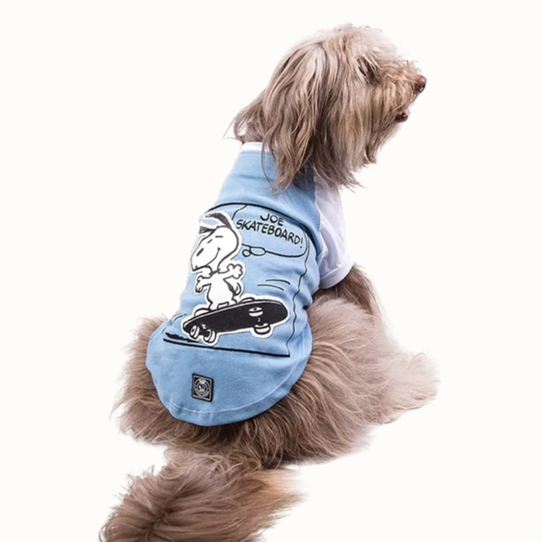 Camisola ZOOZ para cão com design do Snoopy, de cor azul, com detalhes em branco. Estampa divertida do personagem a andar de skate. Vista das costas de um cão, sobre fundo branco.