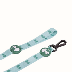 Trela Zooz, em padrão azul claro e verde claro e figuras do snoopy. Vista em detalhe, sobre fundo branco.