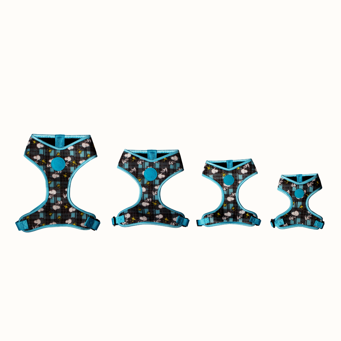 Arnês Corporal Zooz, em padrão azul e preto, com figuras do snoopy e do Woodstock, em vários tamanhos. Vista de frente, sobre fundo branco.