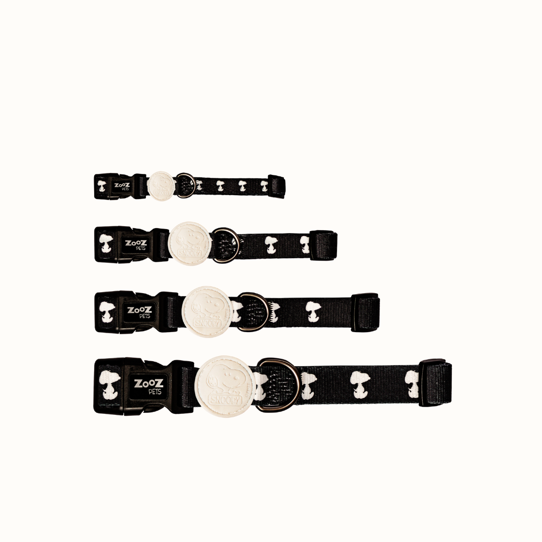 Coleira Zooz, de padrão preto e bege, com detalhes vermelhos e com figuras do snoopy, de vários tamanhos.
Vista frontal, sobre fundo branco.