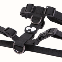 Arnês Snoopy Zooz, de cor preta do snoopy. Vista em detalhe, sobre fundo branco.