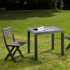 Conjunto de cadeira dobrável e mesa desmontável IPAE PROGARDEN em plástico cinzento, com assento e encosto com ranhuras, exibida em vista frontal ligeiramente inclinada para a direita.