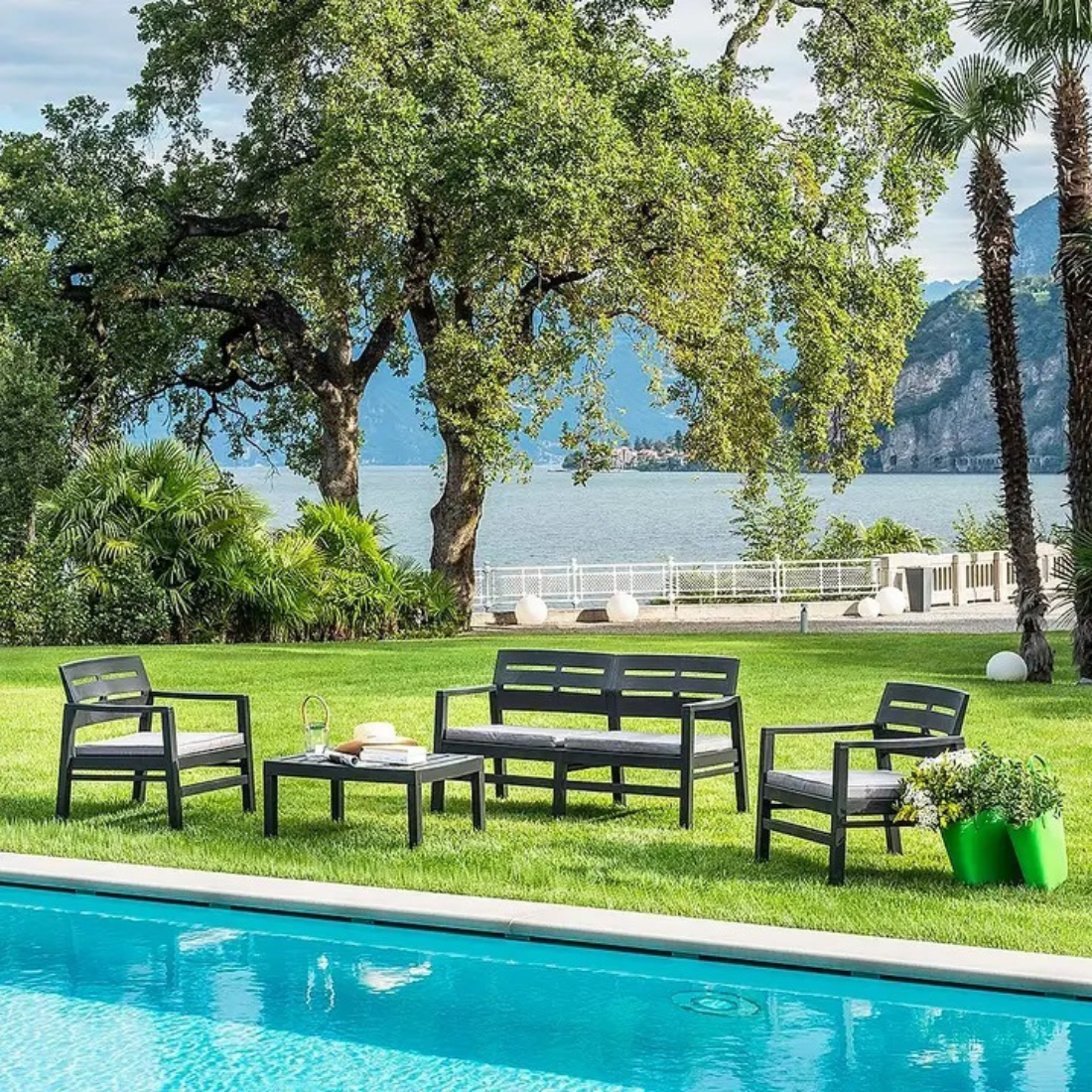 Conjunto composto por 2 cadeiras, 1 cadeira dupla com braços e encosto de apoio, acompanhadas de almofadas no assento, e uma mesa baixa IPAE PROGARDEN. Exibido em ambiente exterior.