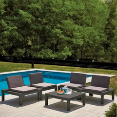 Conjunto de 4 cadeiras e uma mesa em modulo IPAE PROGARDEN, da cor cinzenta e com almofada no assento e no encosto. Exibida em ambiente exterior.