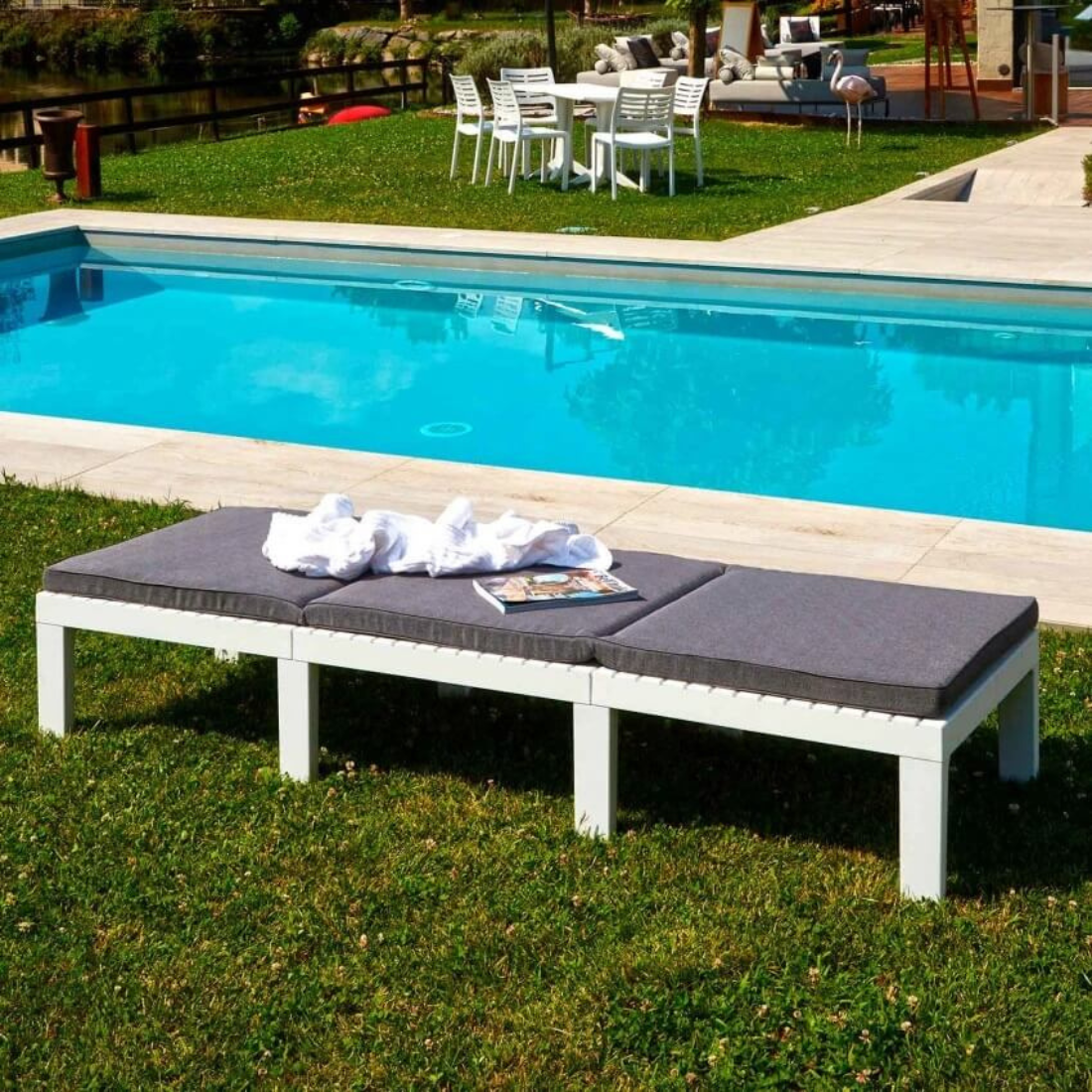 Espreguiçadeira IPAE PROGARDEN em branco, com estrutura resistente, encosto reclinável e com almofada cinzenta. Exibida sem inclinação do encosto e em ambiente exterior.