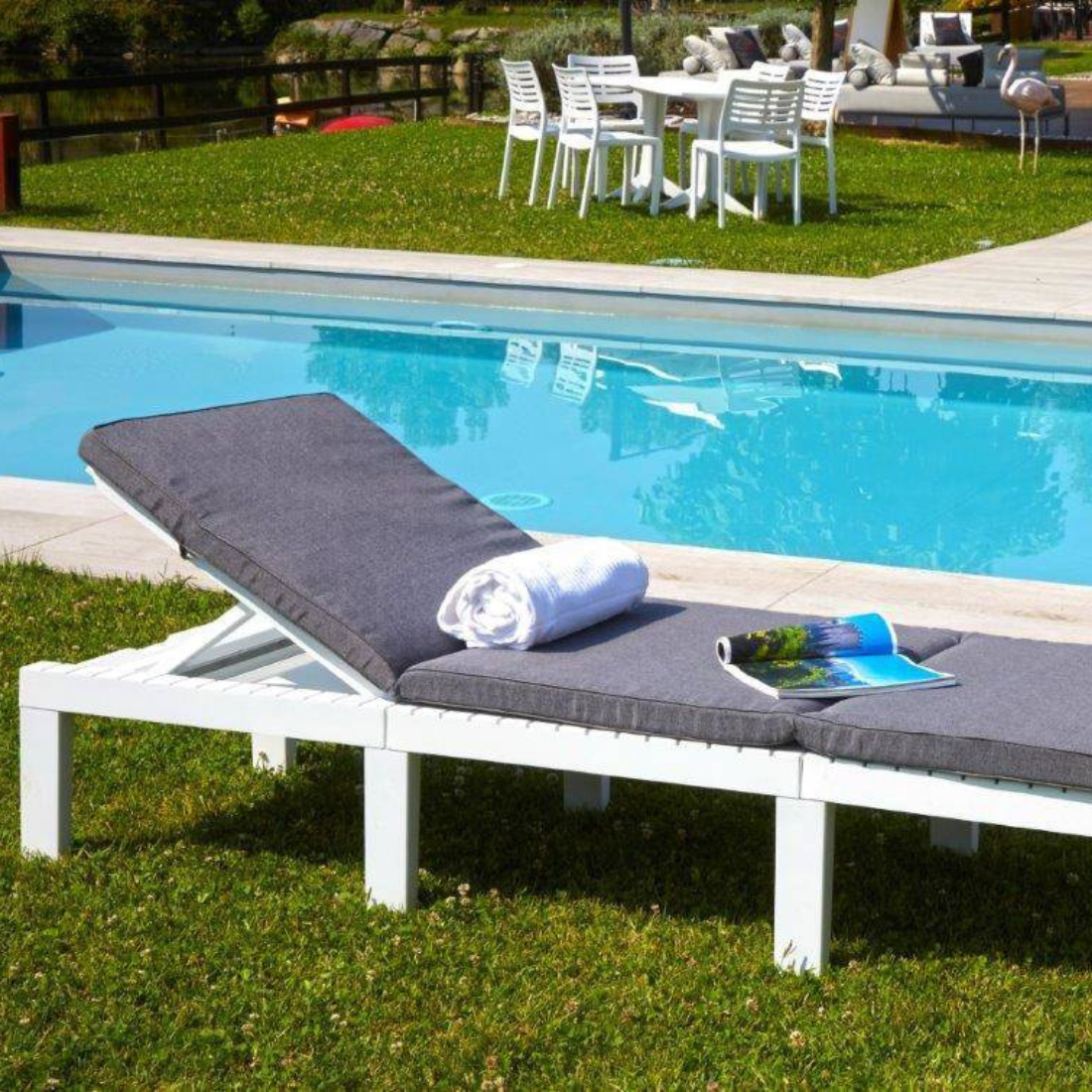 Espreguiçadeira IPAE PROGARDEN em branco, com estrutura resistente, encosto reclinável e com almofada cinzenta. Exibido em ambiente exterior.