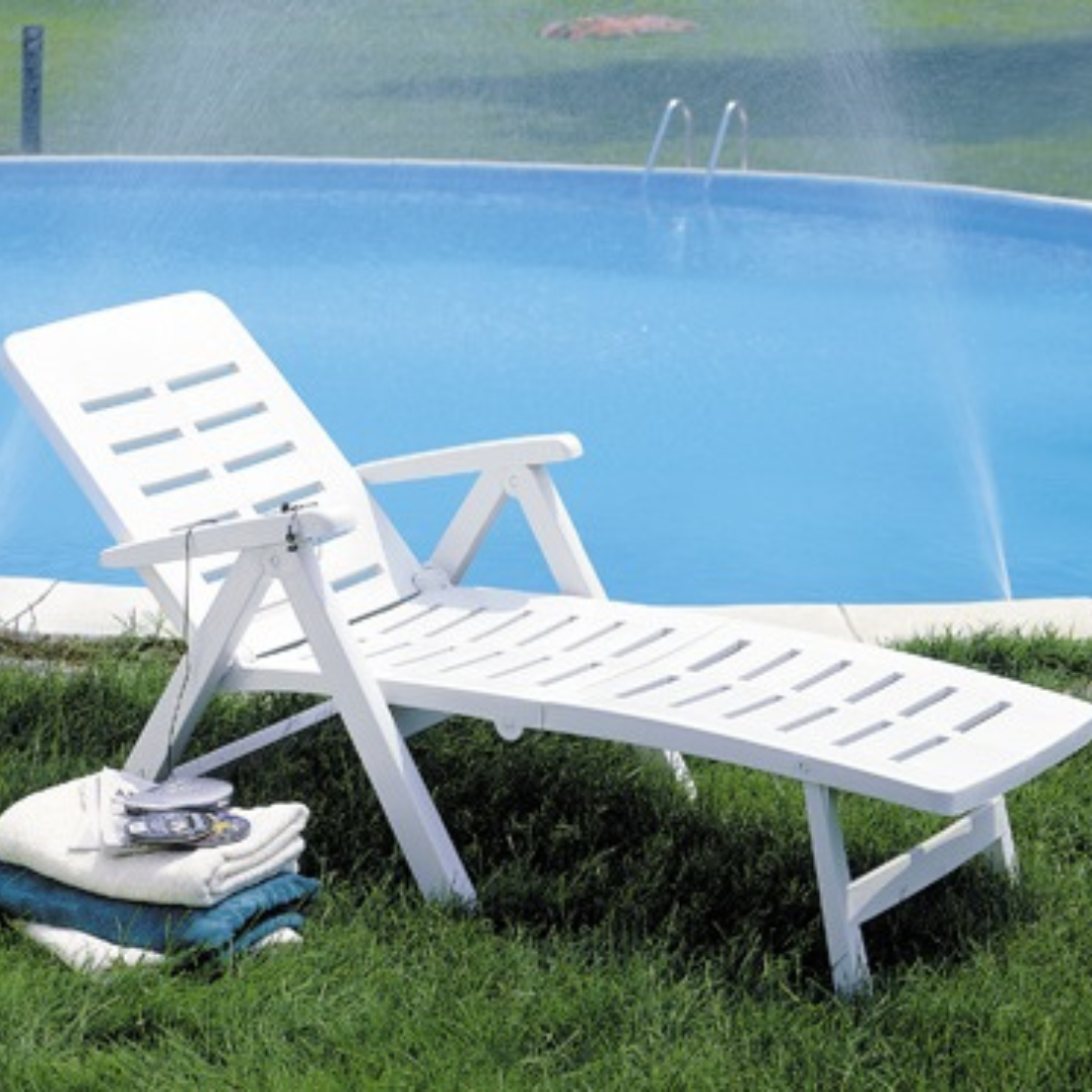 Espreguiçadeira IPAE PROGARDEN com ranhuras plástico, da cor branca, braços laterais e encosto ajustável. Exibido em ambiente exterior.