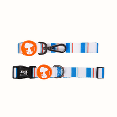 Coleira Zooz, em padrão azul branco, com detalhes em cor de laranja e figuras do snoopy. Vista de frente, sobre fundo branco.