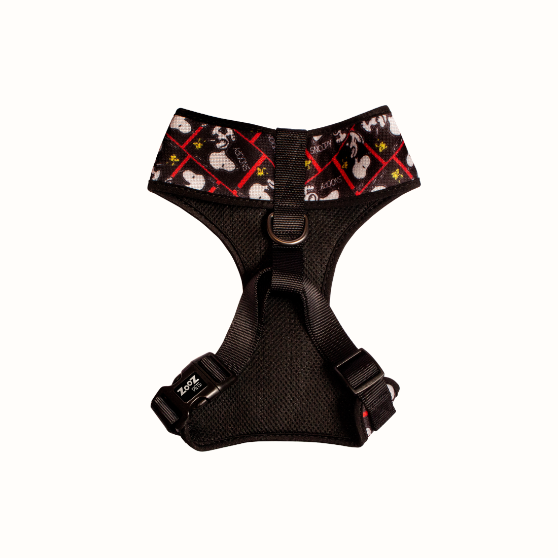 Arnês peitoral Zooz, com o padrão preto e branco, detalhes em vermelho e com figuras do snoopy e forro preto. Vista de frente, sobre fundo branco.
