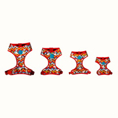 Arnês peitoral Zooz, de cor vermelha, azul, amarela e branca em zig-zag com detalhes do personagem. Vista de frente, vários tamanhos, sobre fundo branco.