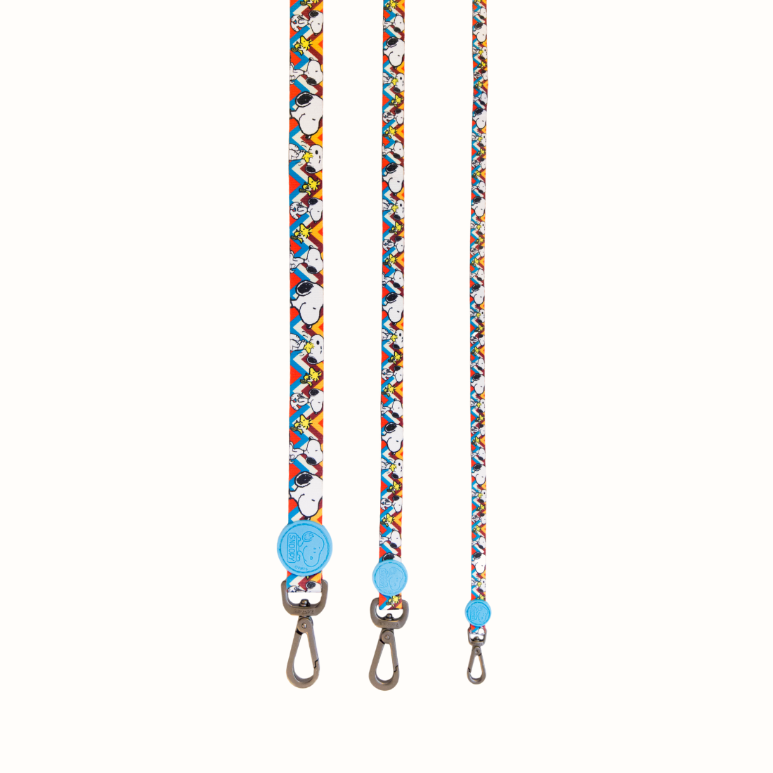 Trela Snoopy Zooz, de cor azul, amarela e branca em zig-zag com detalhes do personagem. Vista de frente, varios tamanhos, sobre fundo branco.