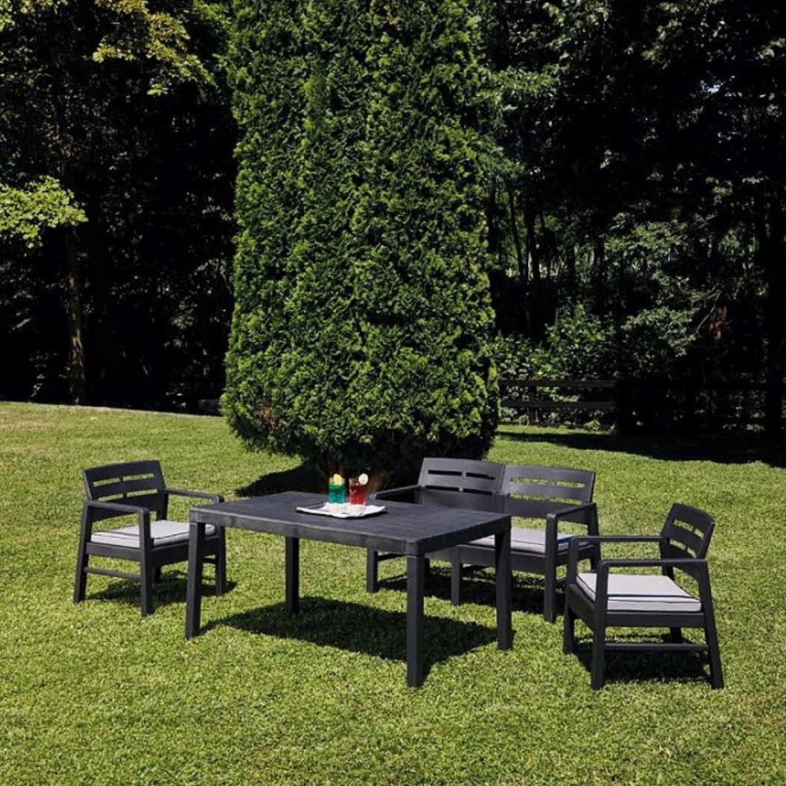 Mesa IPAE PROGARDEN em plástico, de cor preta, com ranhuras no sentido vertical e 4 pés de suporte. Exibido em ambiente exterior. 