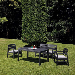 Mesa IPAE PROGARDEN em plástico, de cor preta, com ranhuras no sentido vertical e 4 pés de suporte. Exibido em ambiente exterior. 