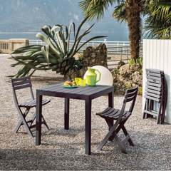 Mesa quadrada IPAE PROGARDEN em plástico, de cor preta, com ranhuras e 4 pés de suporte. Exibido em ambiente exterior. 