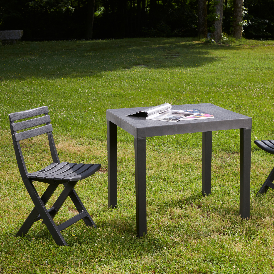 Conjunto de cadeira dobrável e mesa desmontável IPAE PROGARDEN em plástico cinzento, com assento e encosto com ranhuras, exibida em vista frontal ligeiramente inclinada para a direita. 