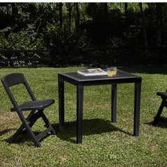 Conjunto de mesa desmontável e duas cadeiras  dobráveis IPAE PROGARDEN em plástico, de cor cinzenta, com acabamento trançado. Exibido em ambiente exterior.