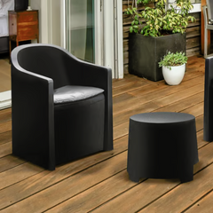 Cadeira curva e uma mesa redonda IPAE PROGARDEN, em preto, acompanhadas de duas almofadas cinzentas no assento. Exibido em ambiente exterior. 