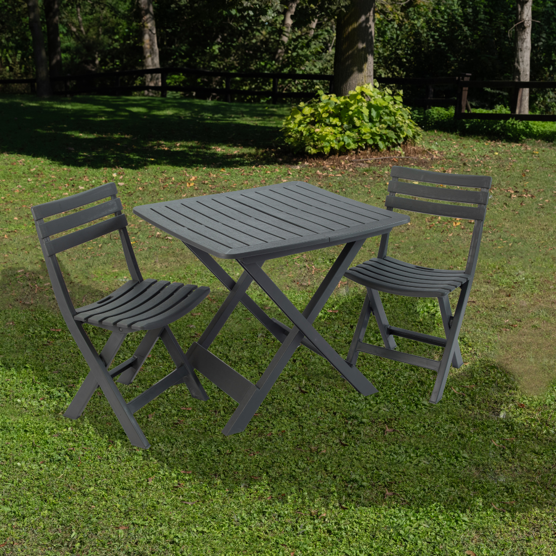 Conjunto de duas cadeiras e uma mesa  dobrável IPAE PROGARDEN em plástico cinzento, com assento e encosto com ranhuras, exibido em ambiente exterior.  