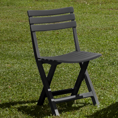 Cadeira dobrável IPAE PROGARDEN, em plástico com efeito madeira, da cor cinza. Exibida em ambiente exterior. 
