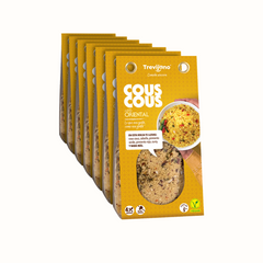 Cous Cous Oriental Trevijano em cartão e embalagem de cartão e plástico transparente, com uma mistura de vegetais desidratados, ervas aromáticas e especiarias orientais. A embalagem tem um rótulo com o nome do produto e informações nutricionais. Fundo branco.