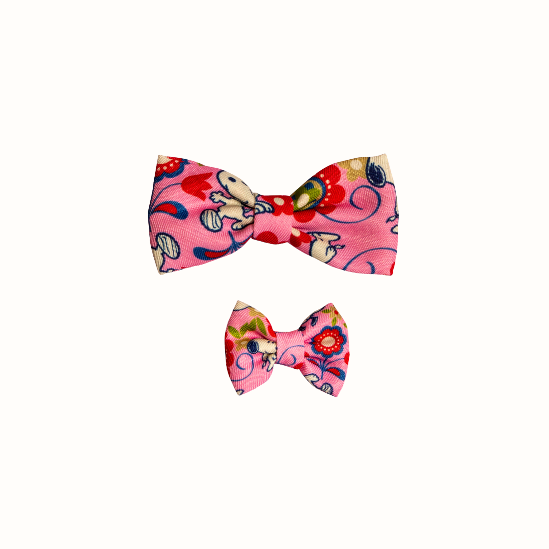 Coleira do Snoopy Zooz para animal, de padrão cor de rosa, floral, com imagens do personagem e um laço do mesmo padrão. Vista frontal, de vários tamanhos, sobre fundo branco. 