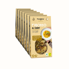 Risotto de All Curry Trevijano em embalagem de cartão e plástico transparente, com uma mistura de arroz, vegetais desidratados e especiarias de curry. A embalagem tem um rótulo com o nome do produto e informações nutricionais. Fundo branco.