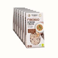 Risotto de Shitake y Boletus Trevijano em cartão e embalagem de plástico transparente, com uma mistura de cogumelos boletos e shitake desidratados. A embalagem tem um rótulo com o nome do produto e informações nutricionais. Fundo branco.