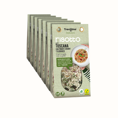 Risotto Toscana em embalagem de cartão e plástico transparente, com uma mistura de vegetais desidratados, frutos secos e manjericão. A embalagem tem um rótulo com o nome do produto e informações nutricionais. Fundo branco.